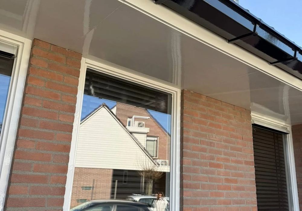 Vers geschilderde witte dakrand en houtwerk aan de buitenkant van een woning